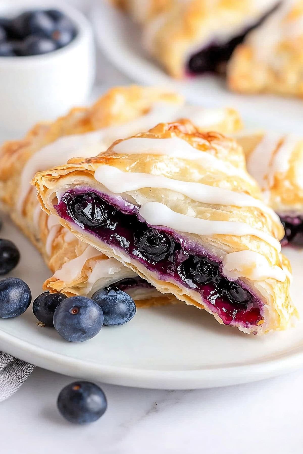 Warm blueberry turnovers drizzled with icing, cut open, close up