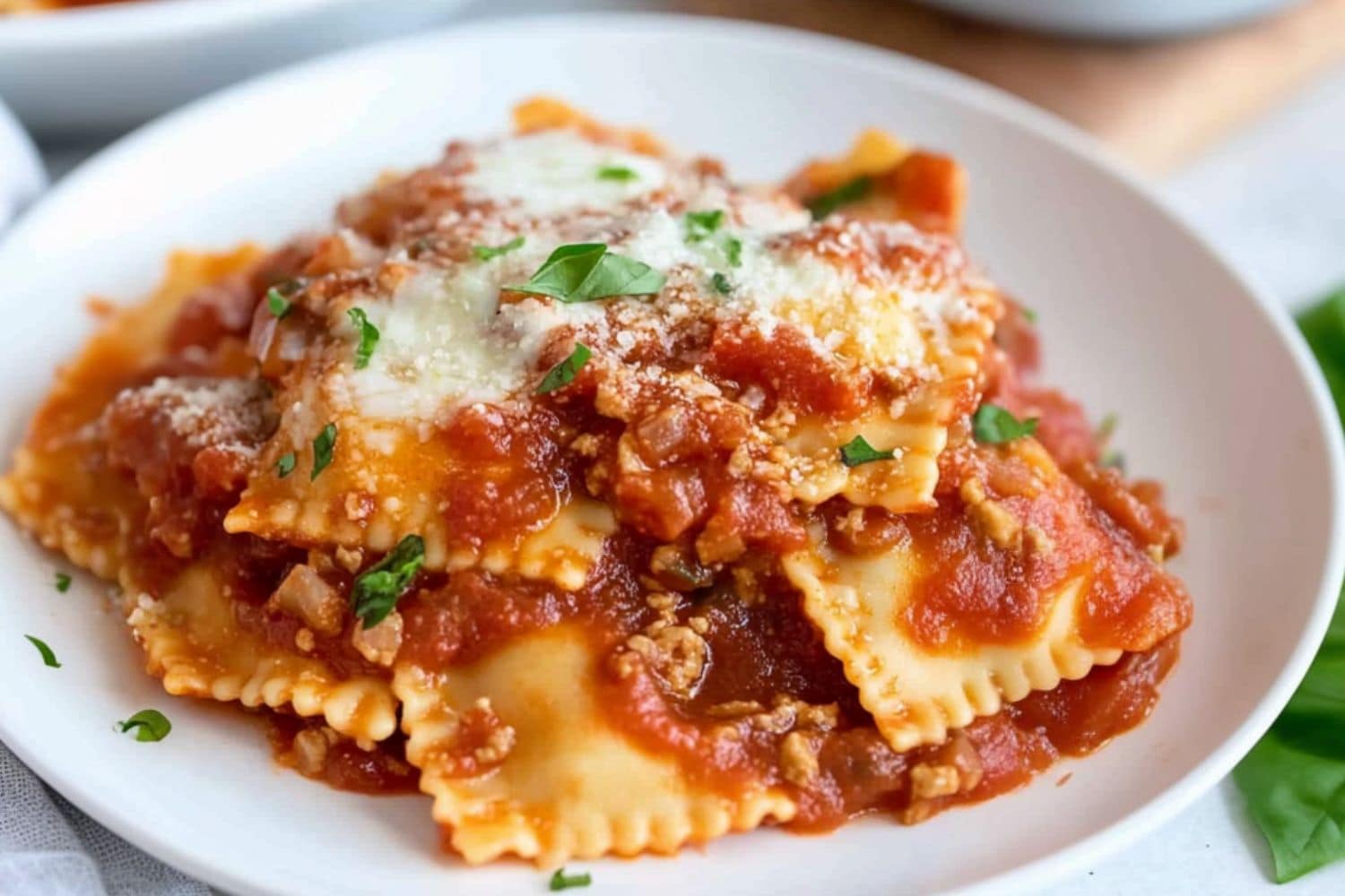 Serving of lazy lasagna made with ravioli pasta and marinara sauce served on a white plate.