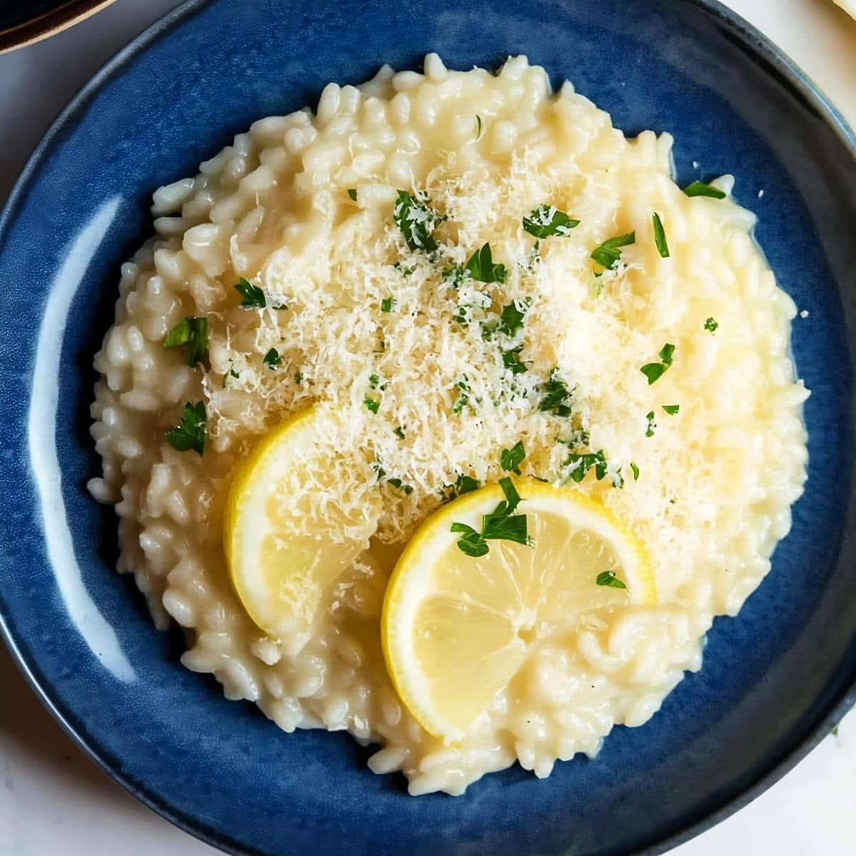 A plate of lemon risotto with a wedge of lemon on the side, top view