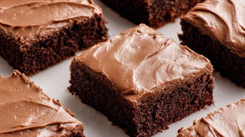 Gooey chocolate brownies with a shiny frosting layer, cut into squares.