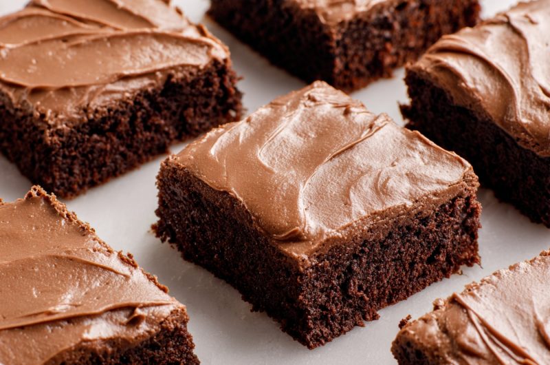 Gooey chocolate brownies with a shiny frosting layer, cut into squares.