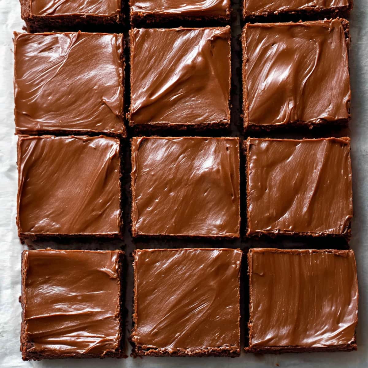 Square slices of Lunch Lady brownies on a white parchment paper.