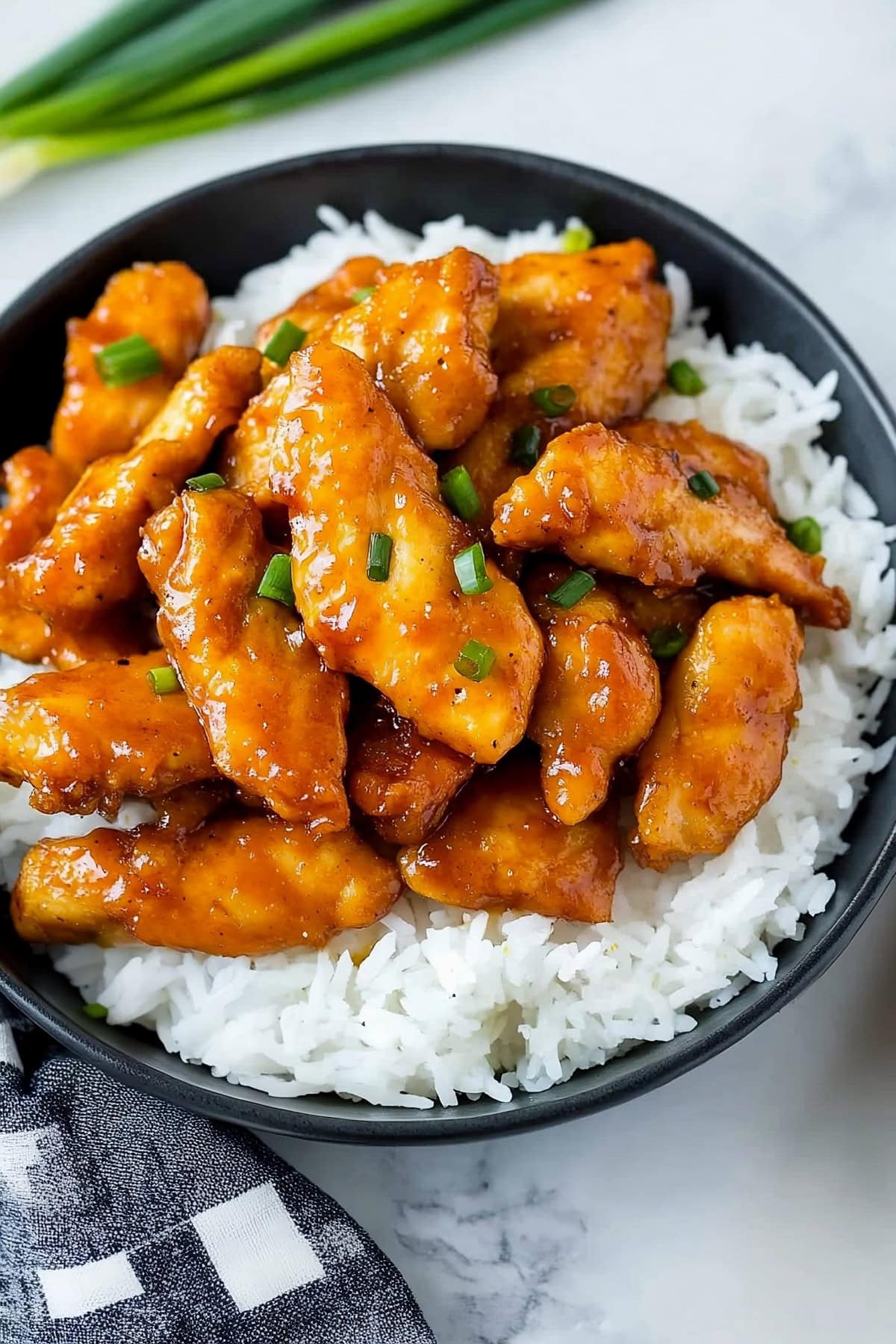 Quick and easy Mongolian chicken served with rice, sprinkled with green onions.