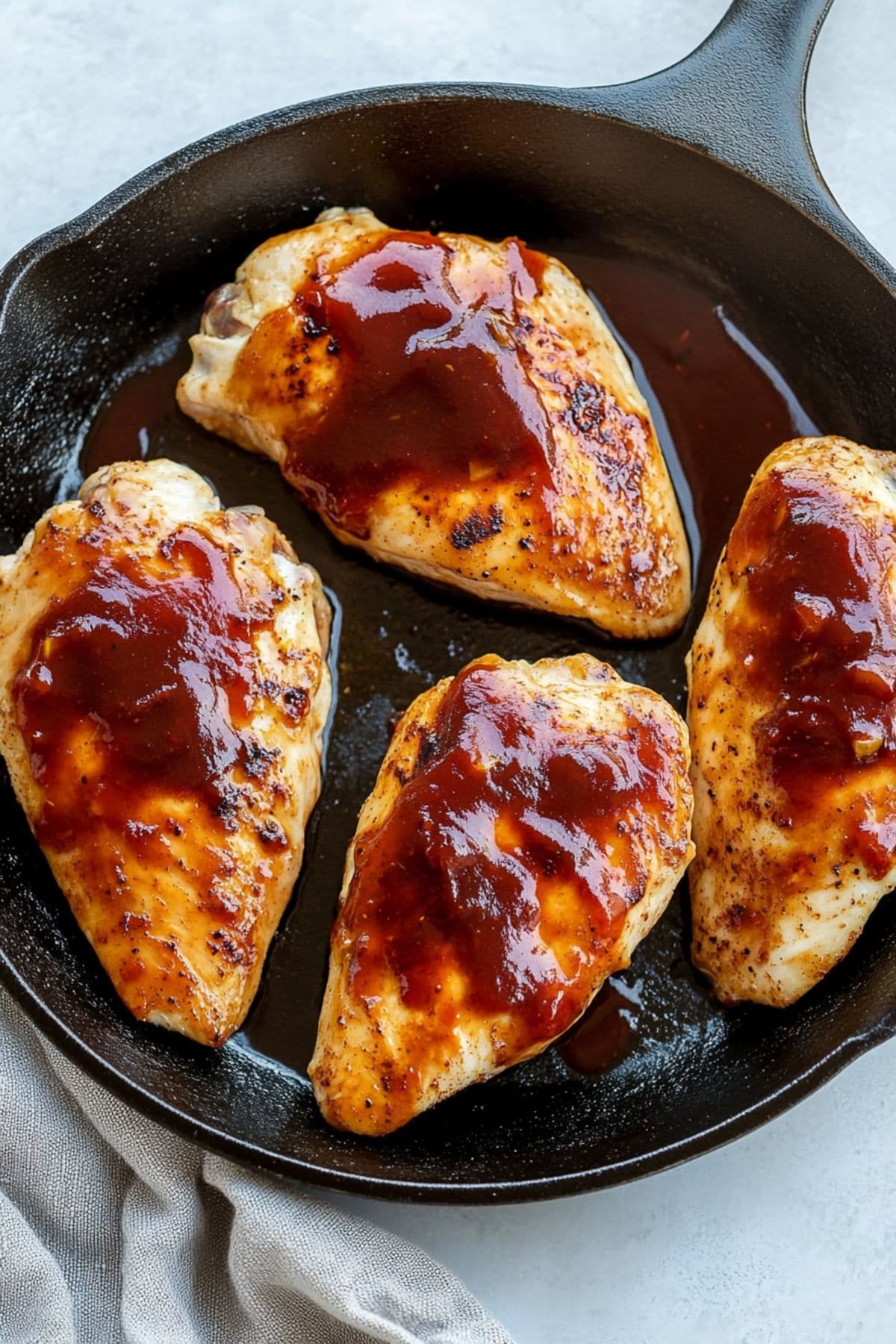 Seared chicken breasts brushed with BBQ sauce in a skillet