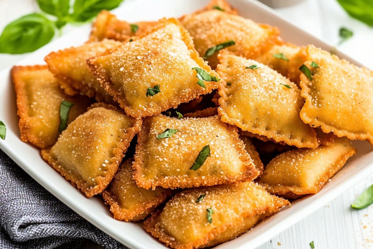 Bunch of crispy toasted ravioli in a white plate.