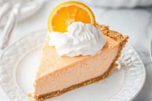 Clean slice of orange creamsicle with whipped cream and orange slice on top.