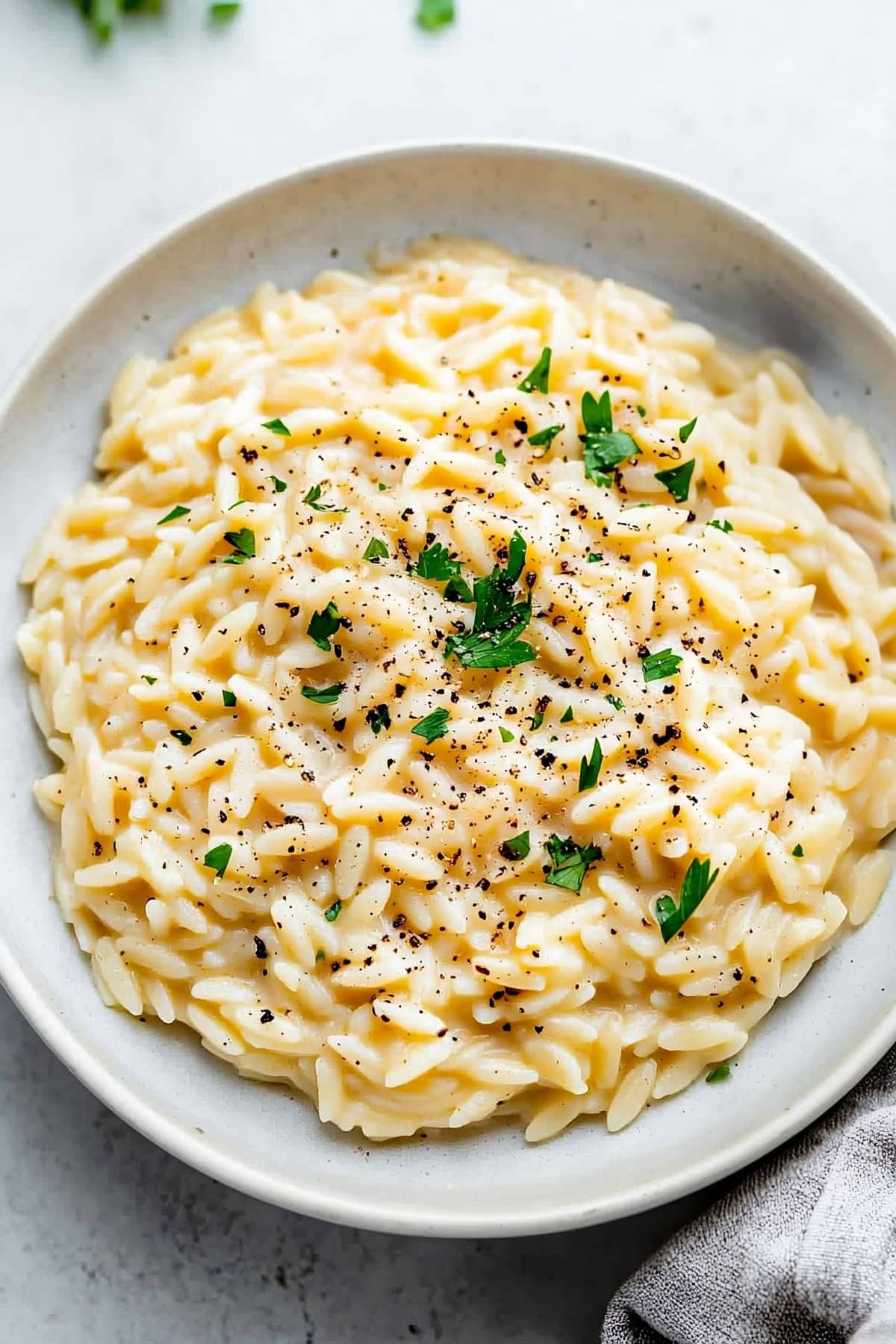 Overhead shot of orzo risotto garnished with fresh herbs, top view