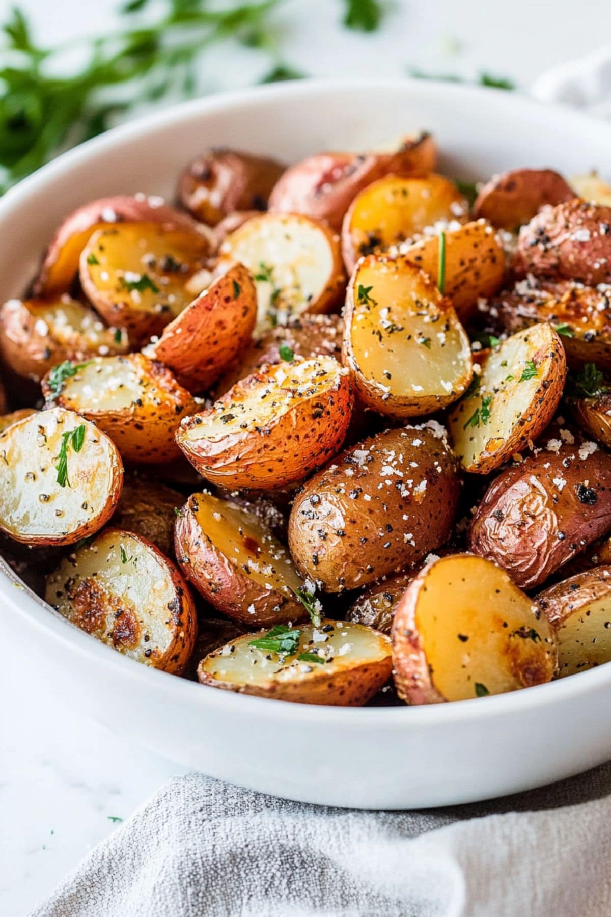 Oven roasted baby red potatoes in a white bowl sprinkled with 
parmesan cheese.