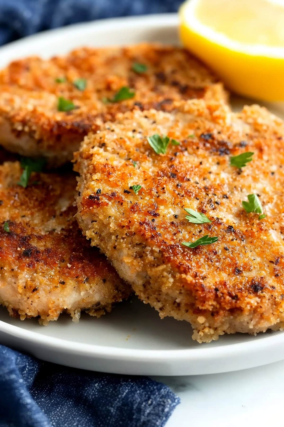 Juicy parmesan-crusted pork chops with a golden crust with a slice of lemon.