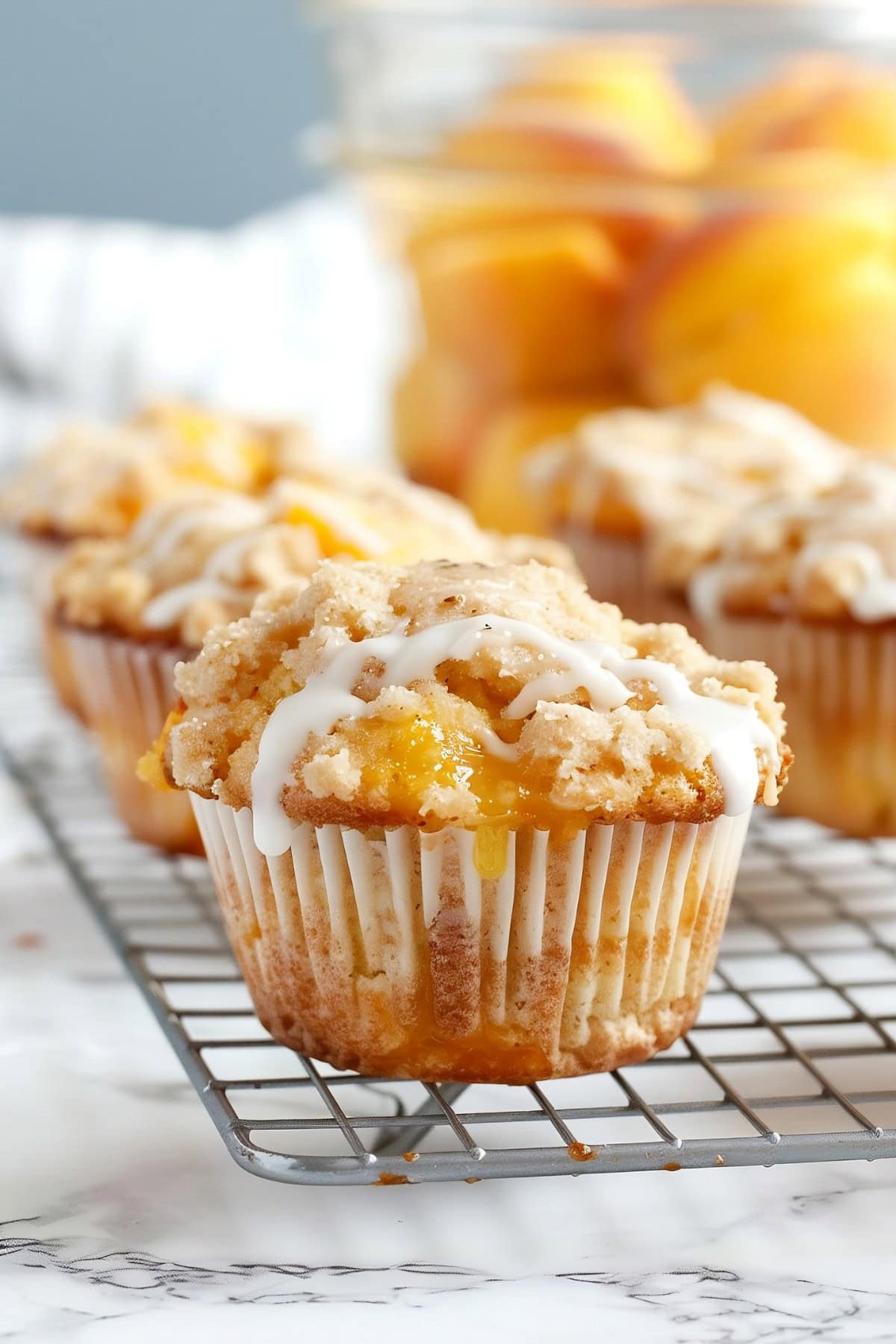 Freshly baked peach streusel muffins cooling on a wire rack.