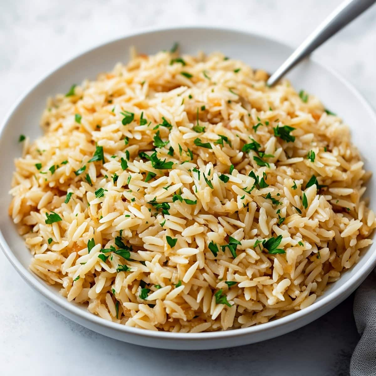 Fluffy rice pilaf served in a deep skillet with a wooden spoon.