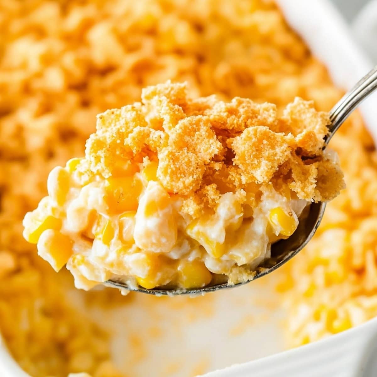 Golden-brown scalloped corn with crackers, on a spoon, close up