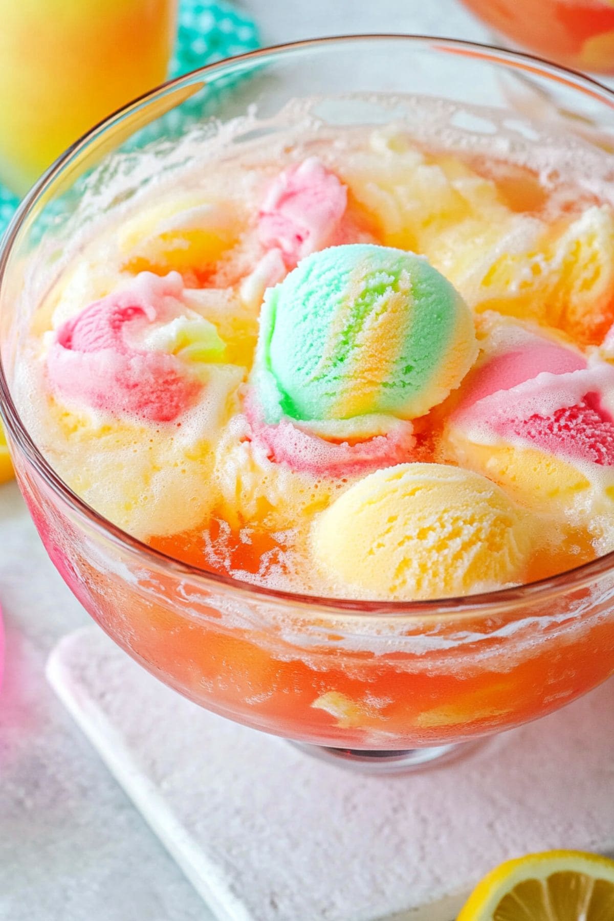 Punch made with pineapple juice, lime soda topped with rainbow colored sherbet served on a large glass punch bowl.