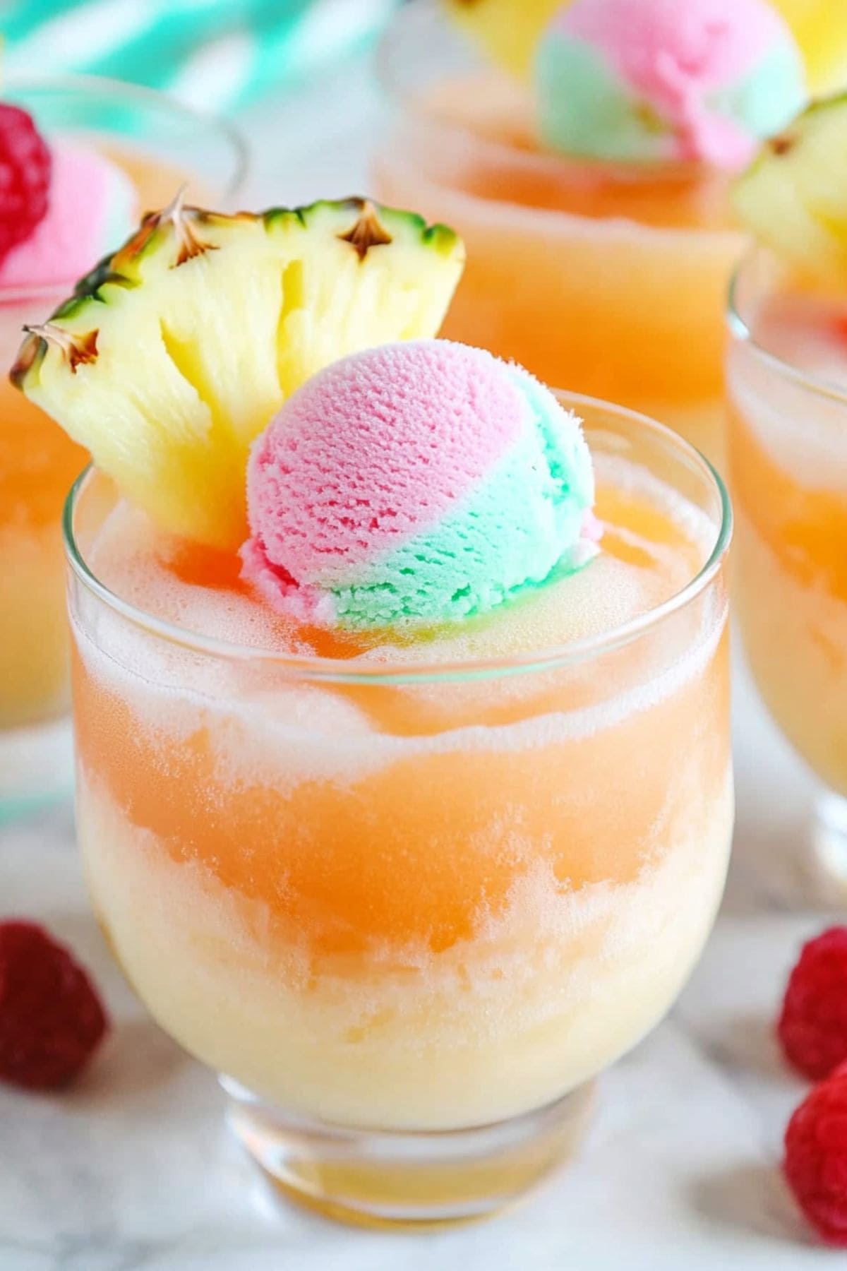 Sherbet punch served in a glass with a scoop of rainbow sherbet, pineapple slice and raspberry on top.