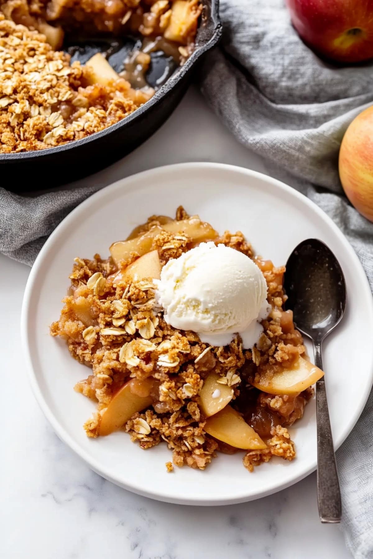 A plate of apple crisp topped with a scoop of ice cream in a plate.