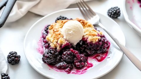 Skillet blackberry cobbler garnished with a scoop of vanilla ice cream served in a white plate.