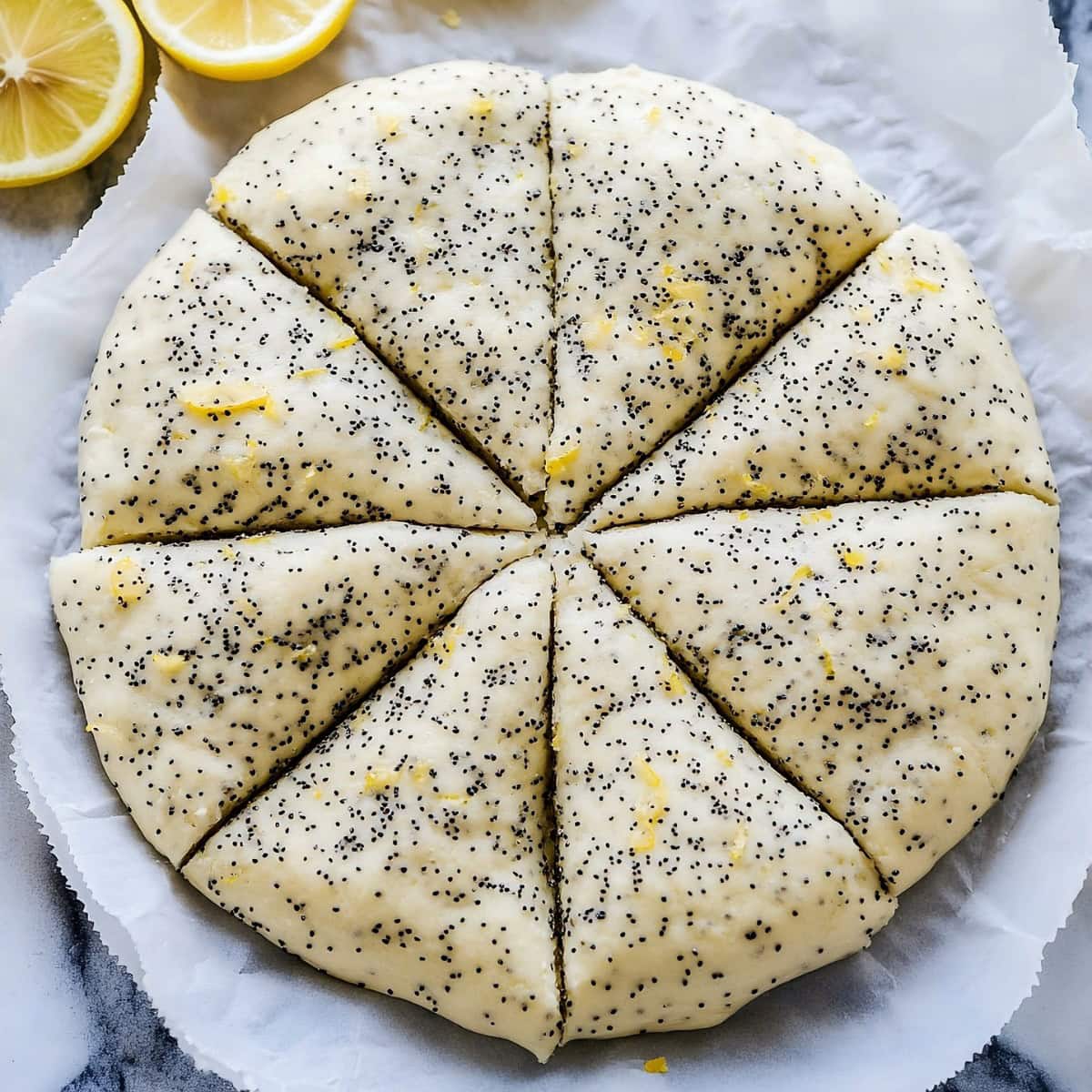 Lemon and poppyseed scone dough with lemon zest rolled into a circle and cut into wedges