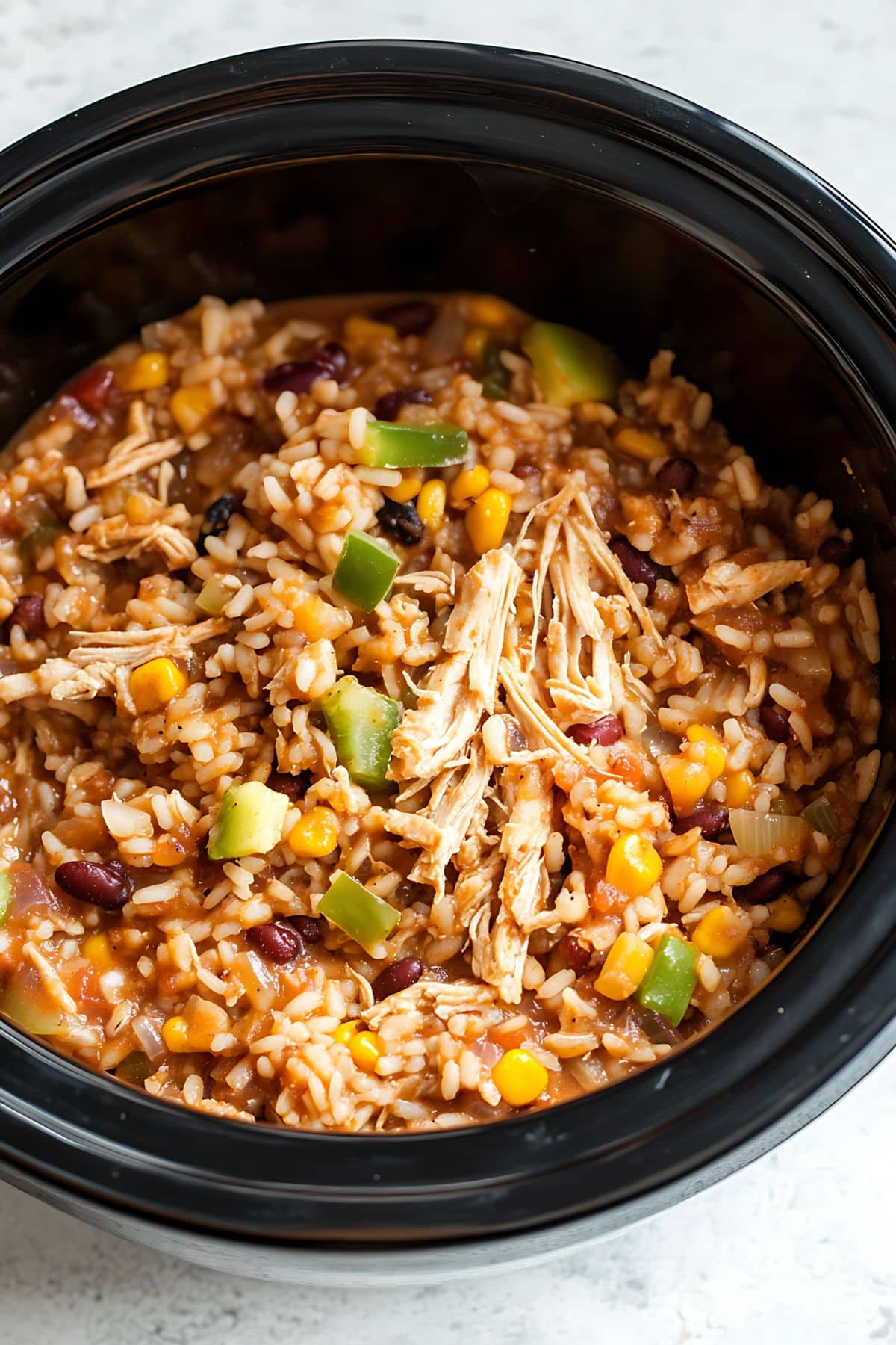 Shredded chicken, onion, bell pepper, pinto beans and instant rice cooked inside a slow cooker.