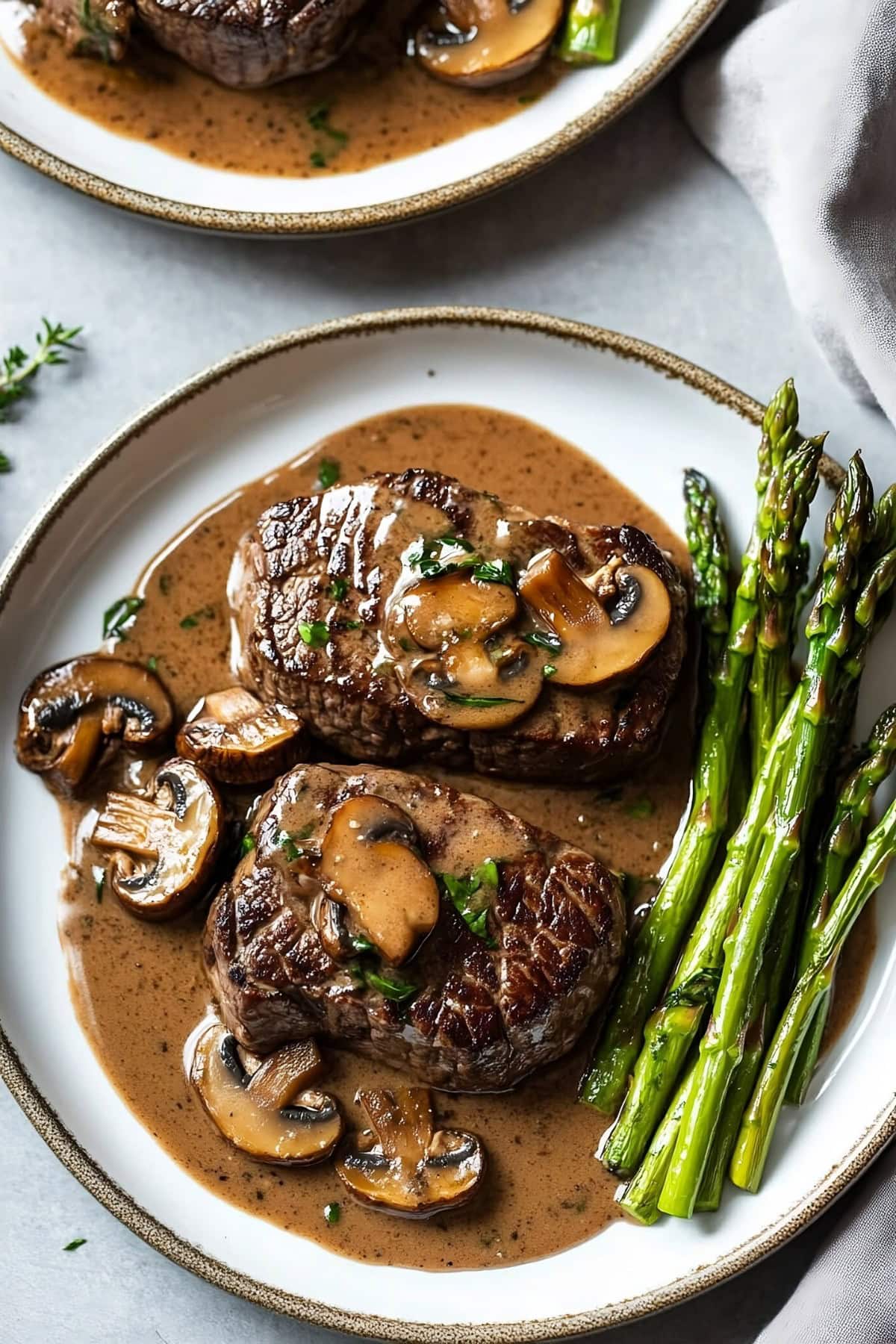 Savory steak Diane with mushrooms and asparagus on a plate.