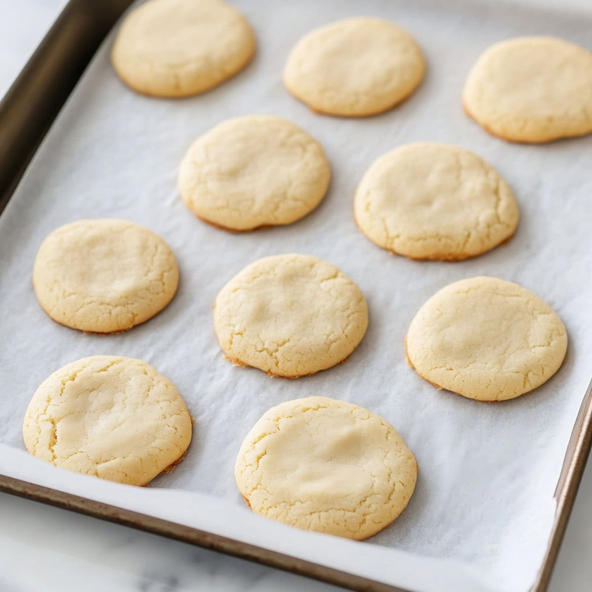 Plain sugar cookies on parchment lined baking sheet.