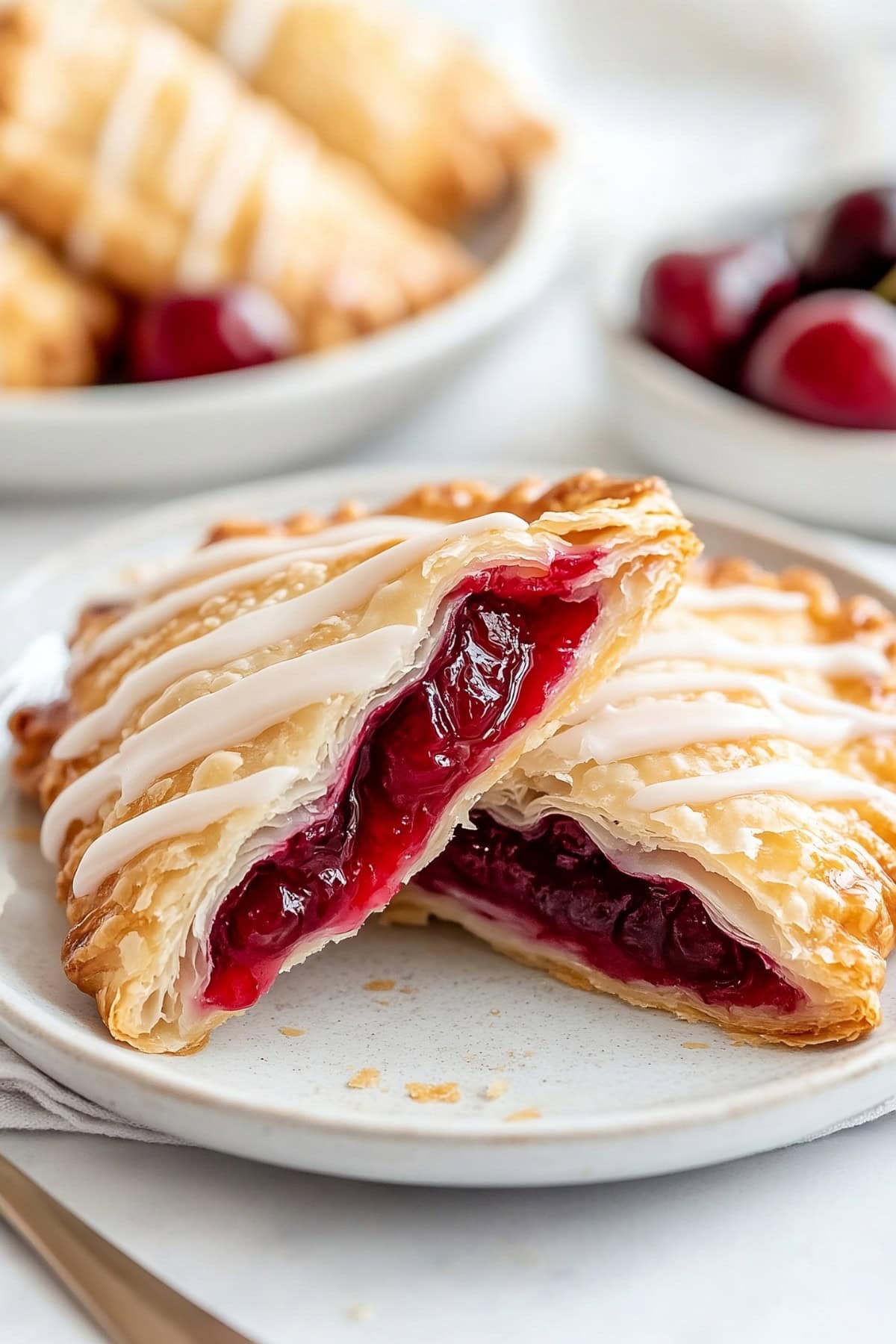 Homemade cherry turnovers filled with sweet, juicy cherries, cut in half on a plate.