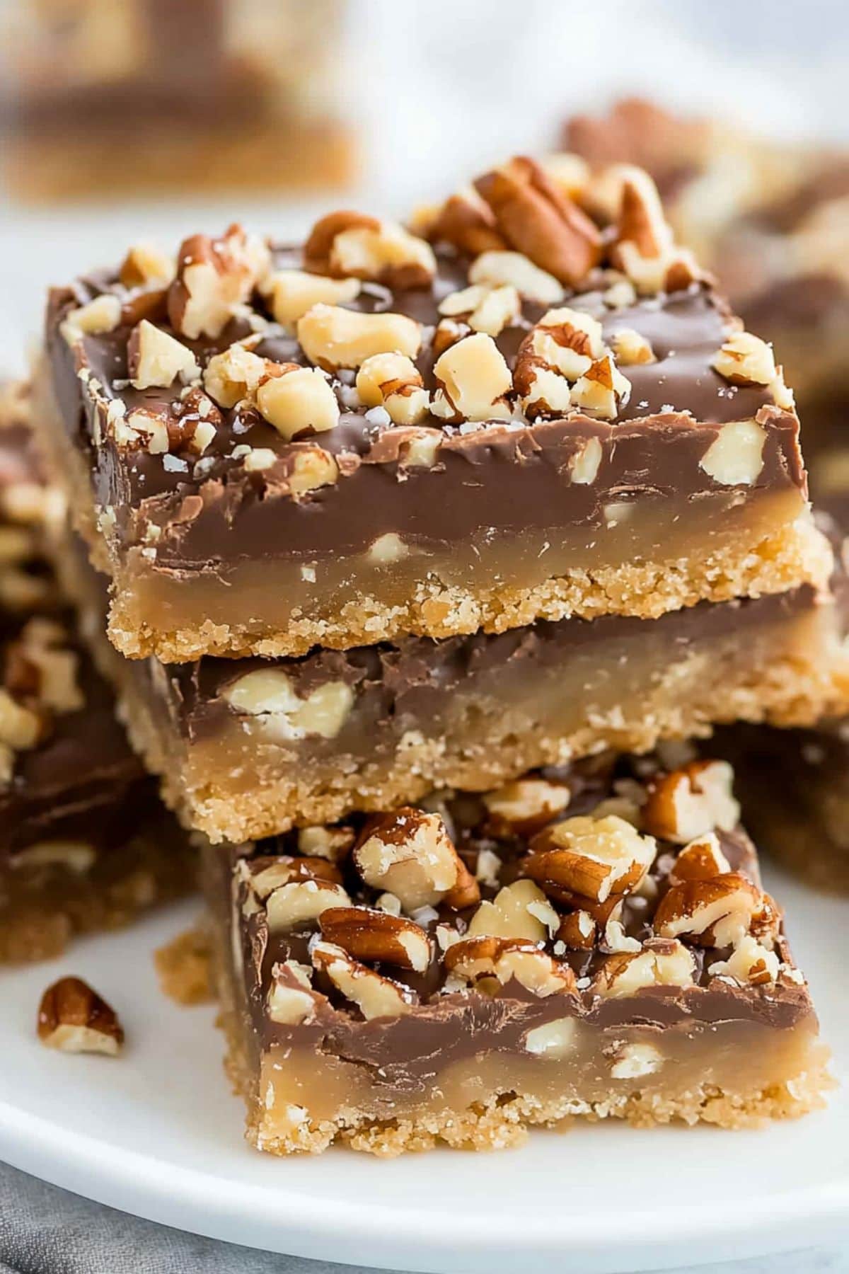 Toffee bar slices stacked on top of each other on a white plate, side view