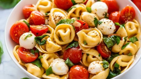 Tortellini caprese salad served in a white bowl.