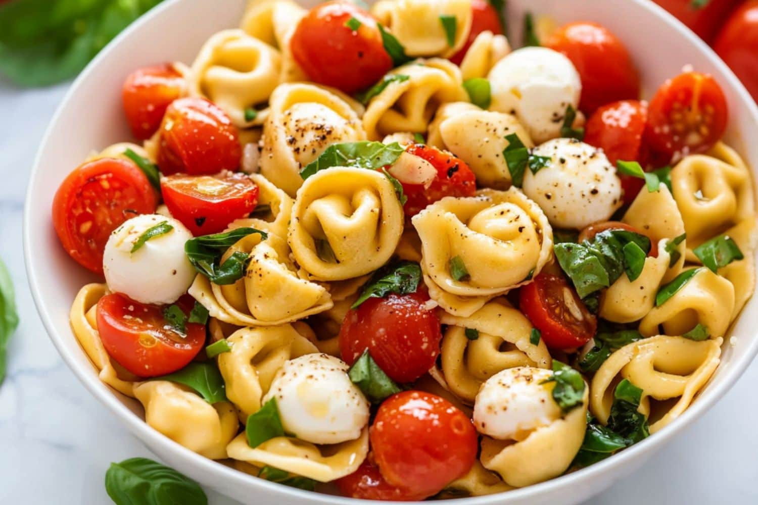 Tortellini caprese salad served in a white bowl.