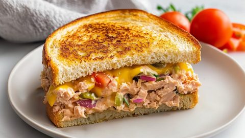 Creamy tuna melt with chopped tomatoes, onions and pickle relish in a plate.