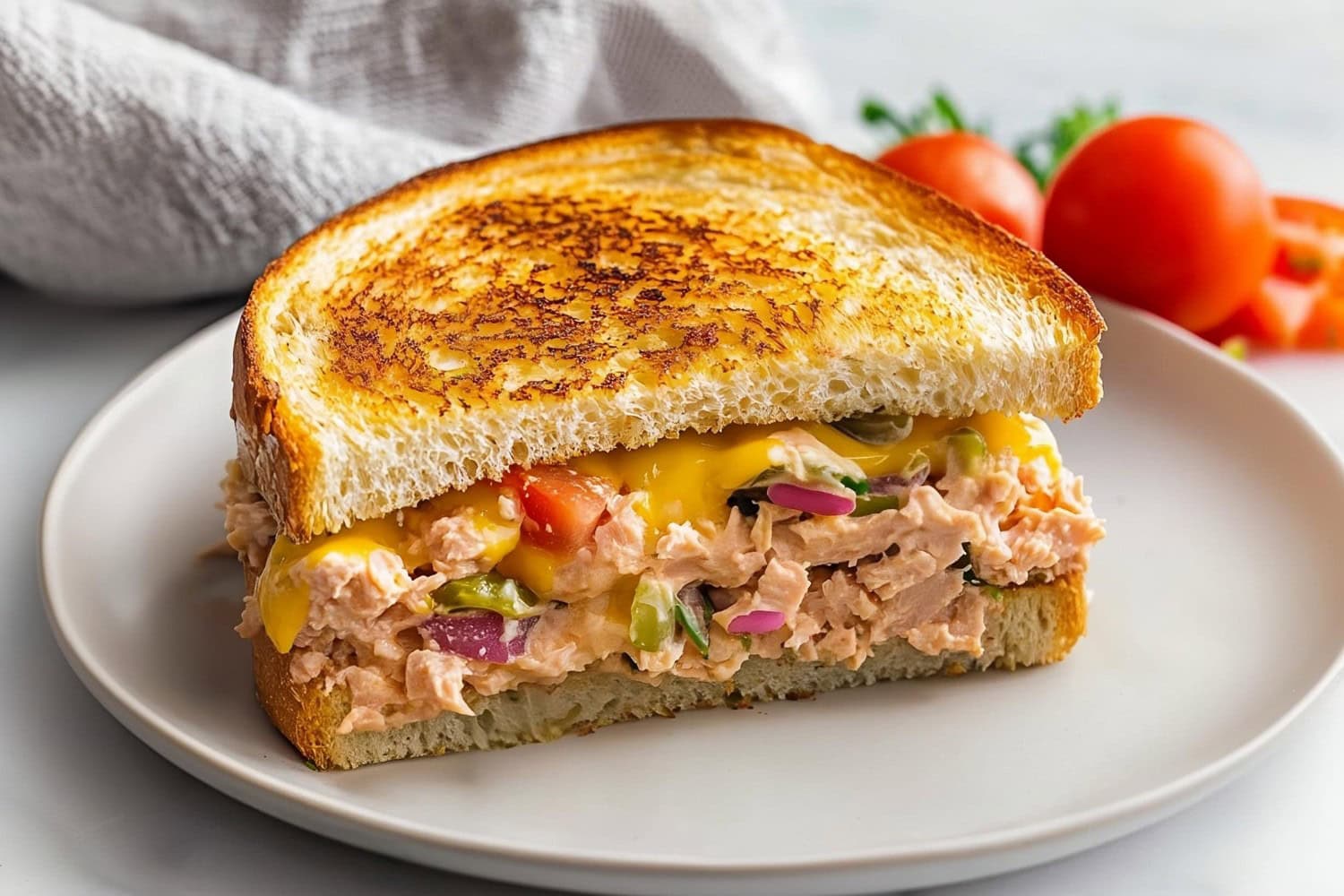 Creamy tuna melt with chopped tomatoes, onions and pickle relish in a plate.