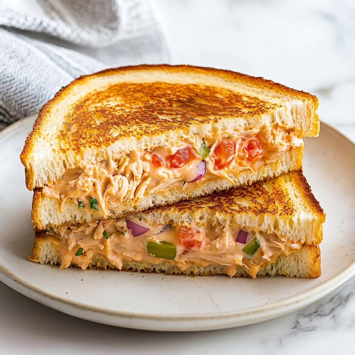 Comforting tuna melt sandwich with melted cheddar and golden, toasted bread.