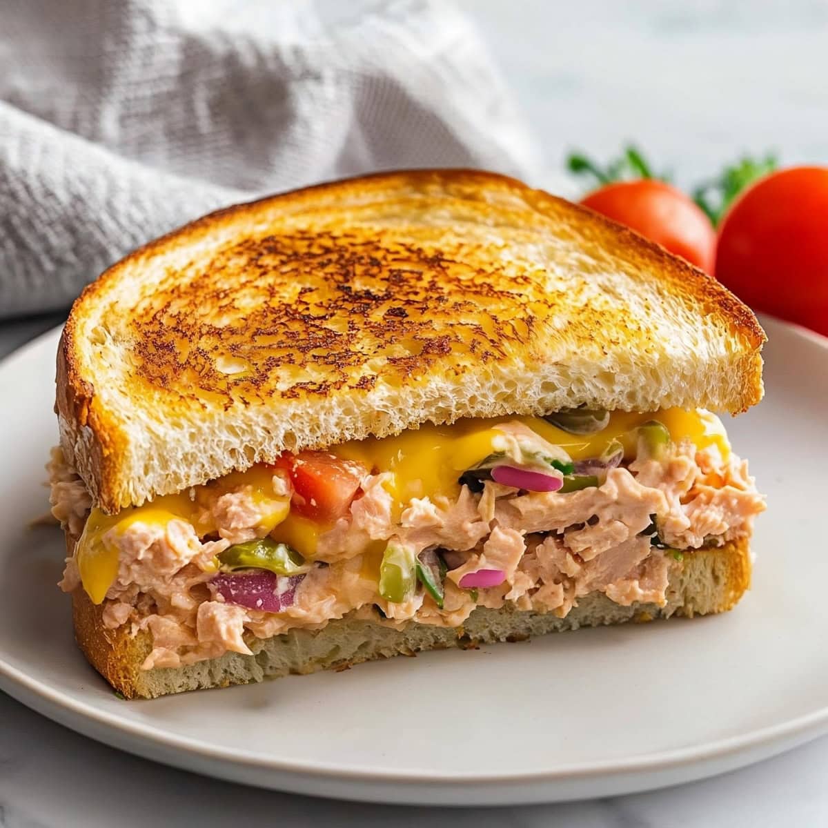 Savory tuna melt sandwich with melted cheddar and vegetables, toasted to golden perfection.