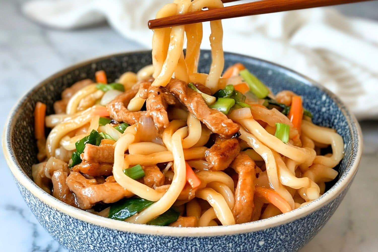 Yaki udon serving with chopsticks in a blue Chinese bowl.