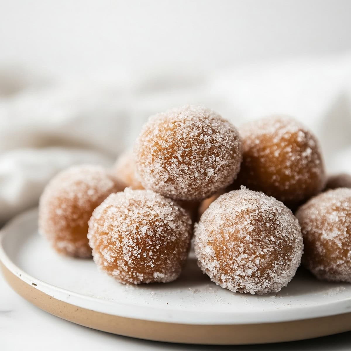 A plate of freshly baked pumpkin spice donut holes covered in sugar, on a plate, side view