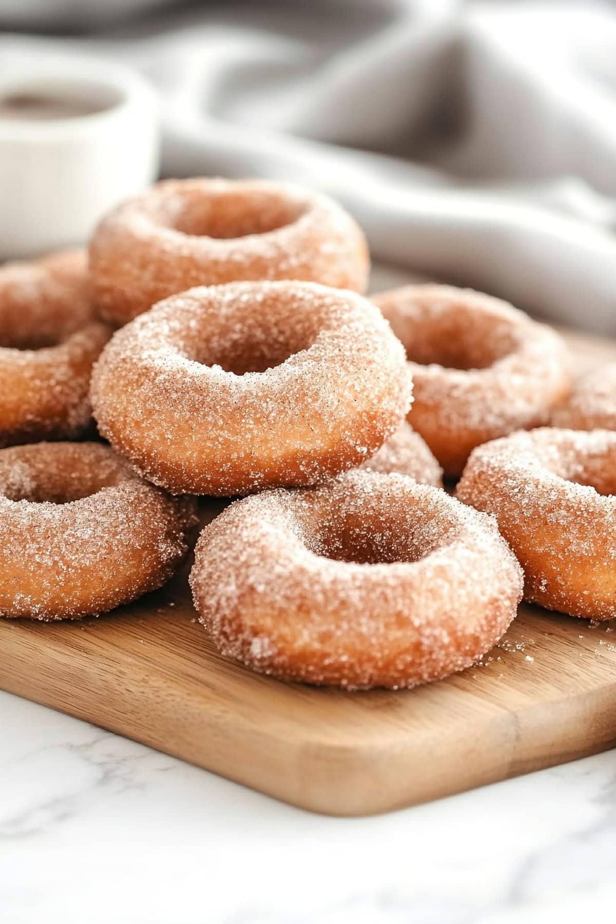 Cinnamon sugar coated donuts served on a wooden board.