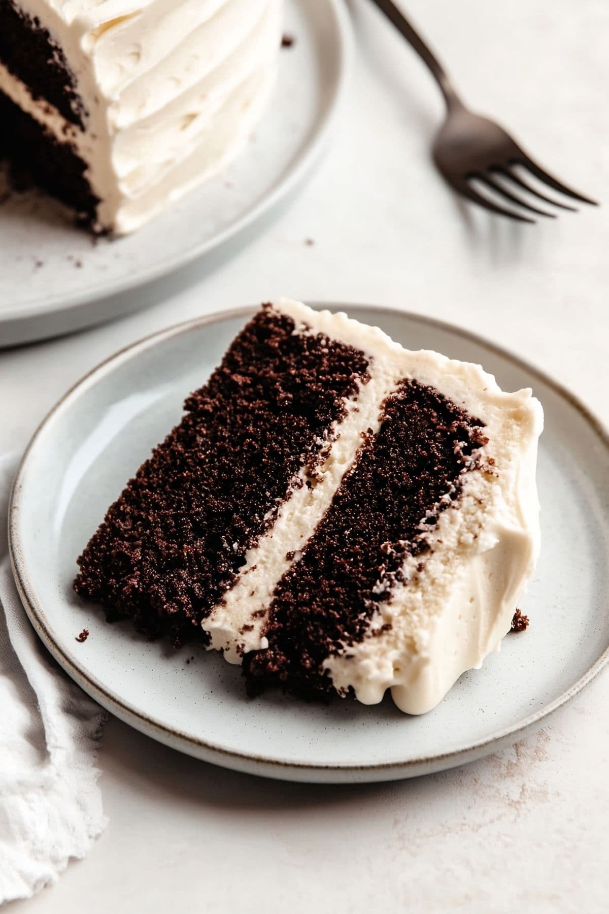 A slice of chocolate cake with cream cheese frosting on a plate