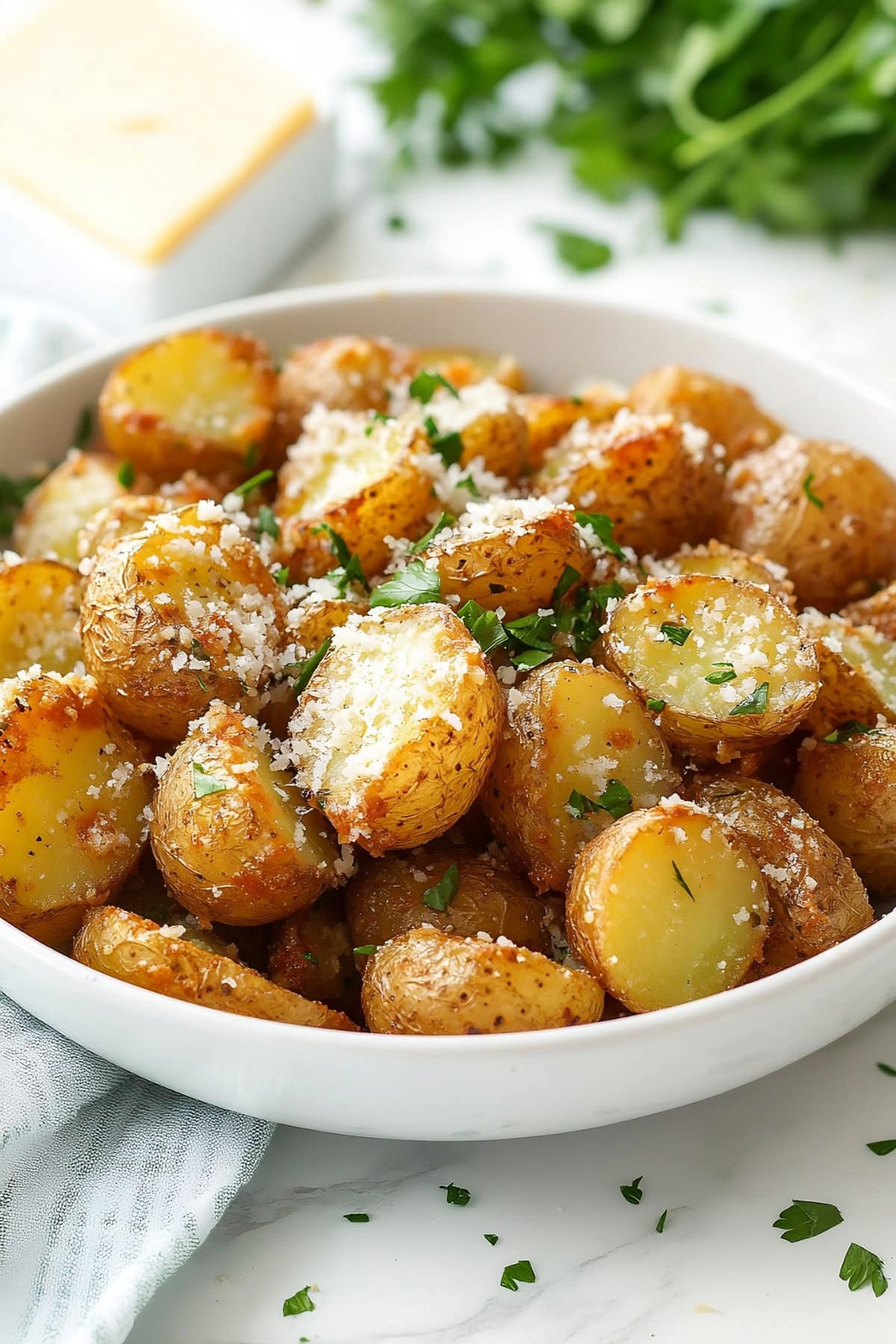 Bowl full of garlic butter potatoes with freshly grated parmesan cheese and fresh herbs