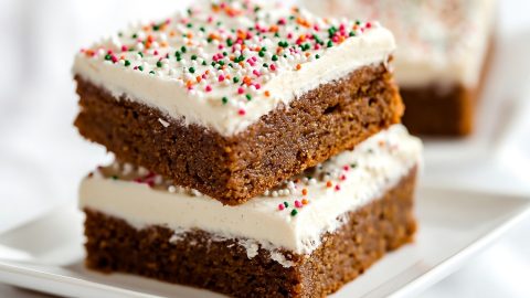 Gingerbread bars with cream cheese served in a square saucer.