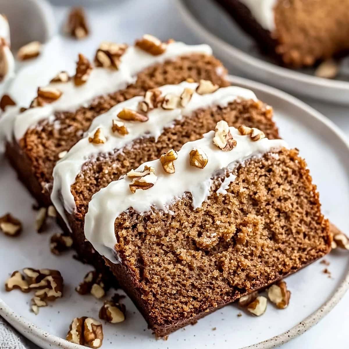 Sliced gingerbread loaf with chopped pecans and cream cheese.