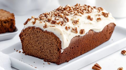 Gingerbread loaf covered with cream cheese and chopped pecans.