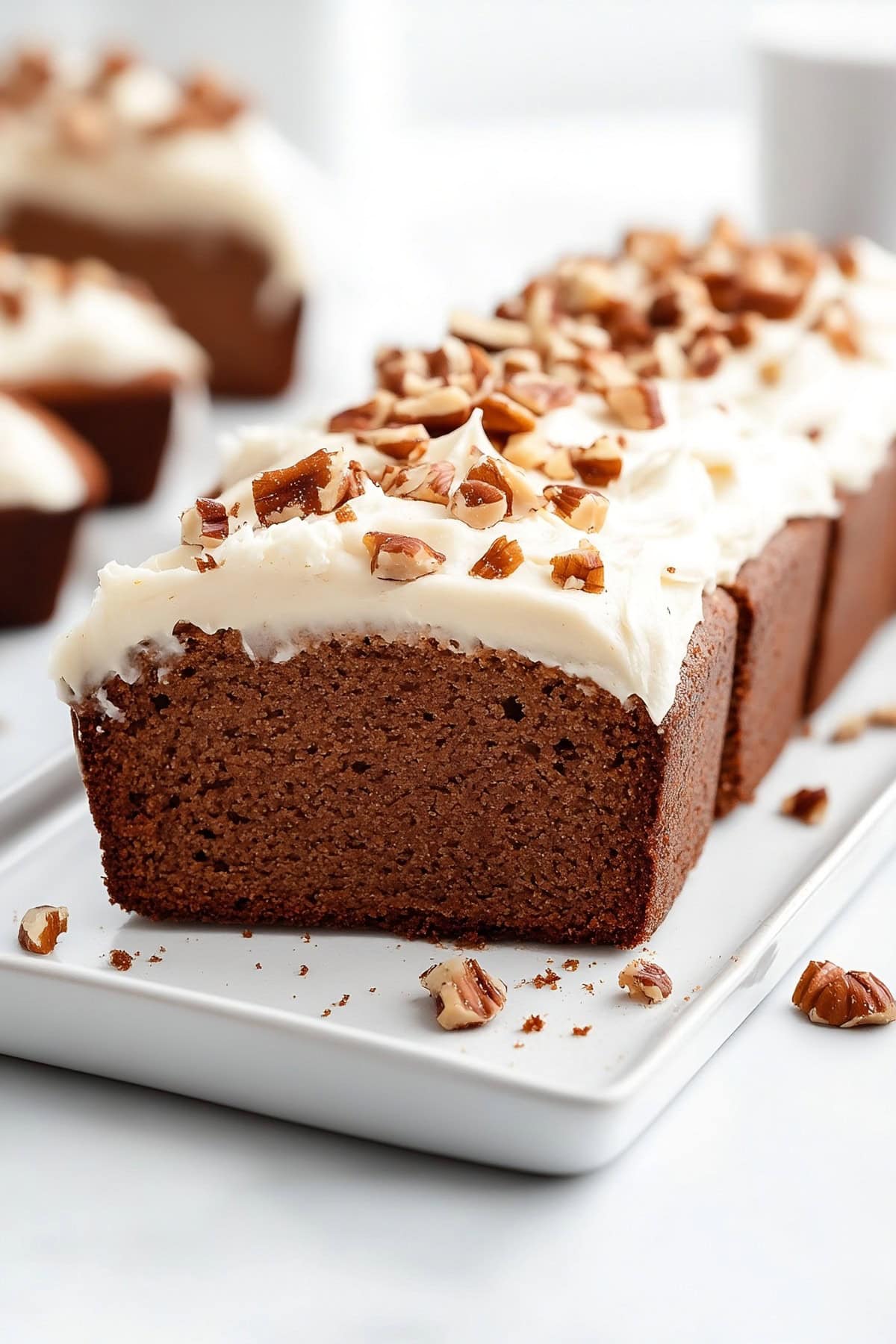 Sliced gingerbread loaf with cream cheese frosting and chopped walnuts