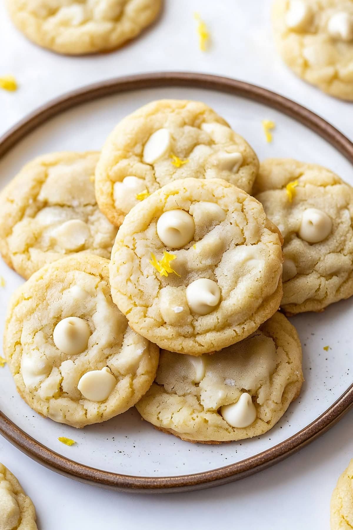 Chewy white chocolate chip cookies on a plate with lemon zest