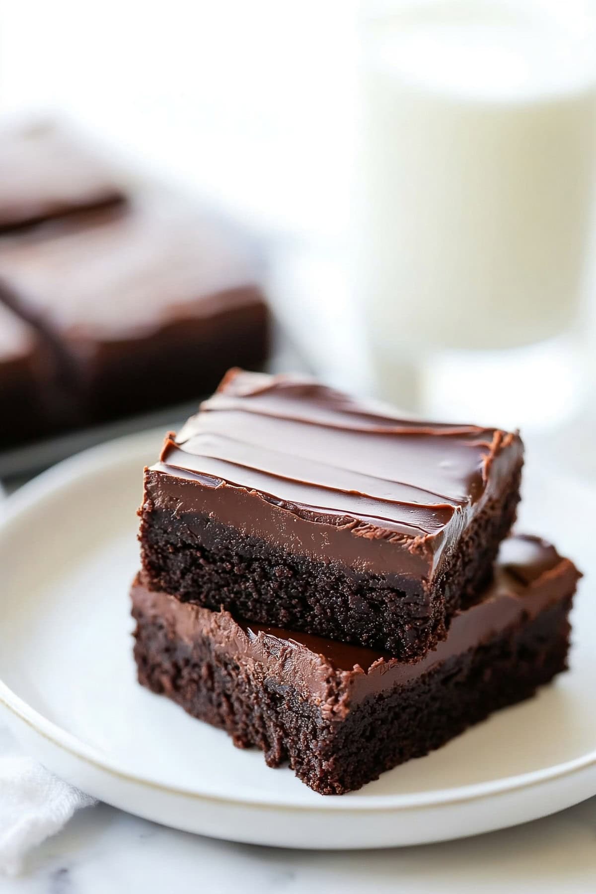 Two slices of fudgy chocolatey brownies served on a white plate.