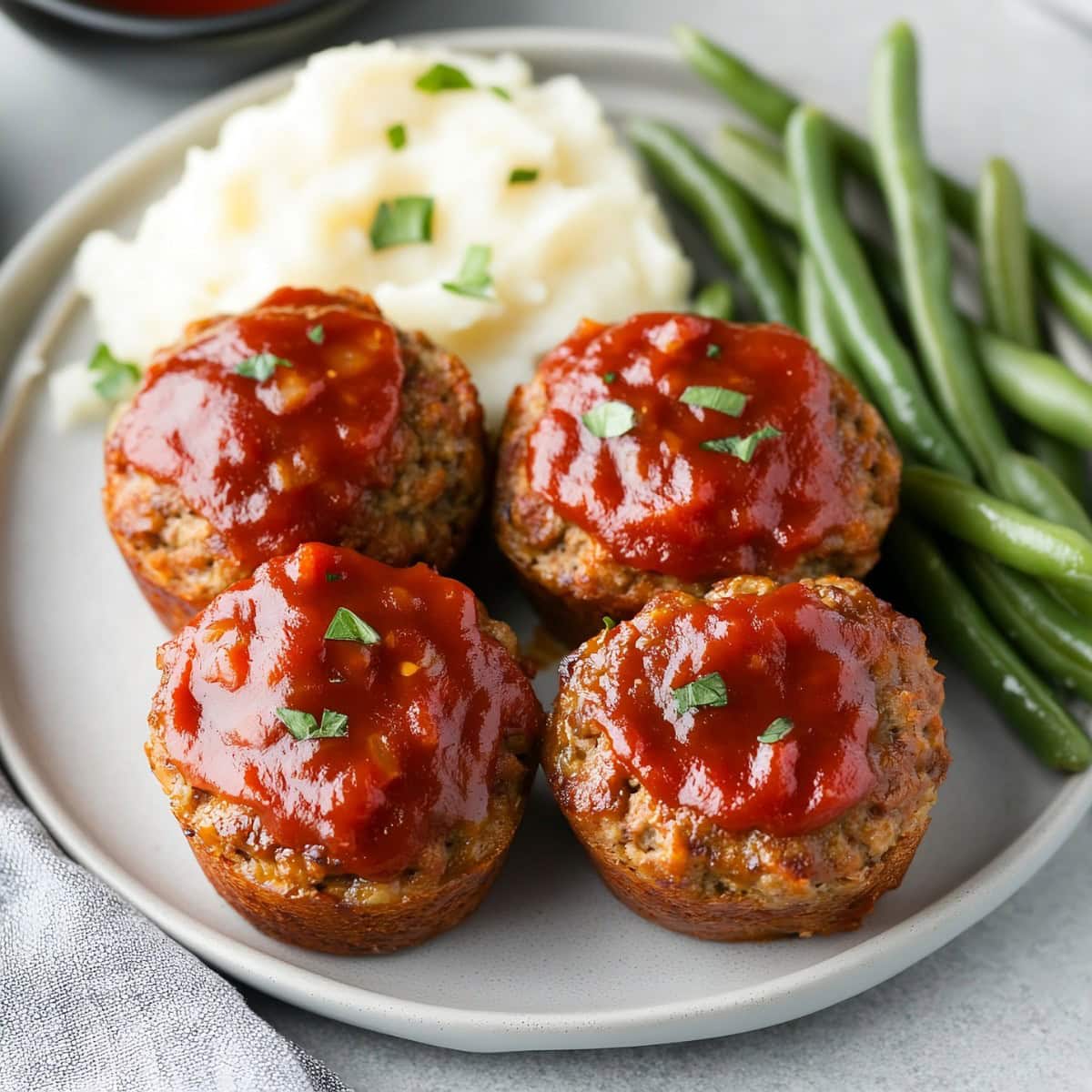 Meatloaf muffins, asparagus and mashed potatoes on a plate.