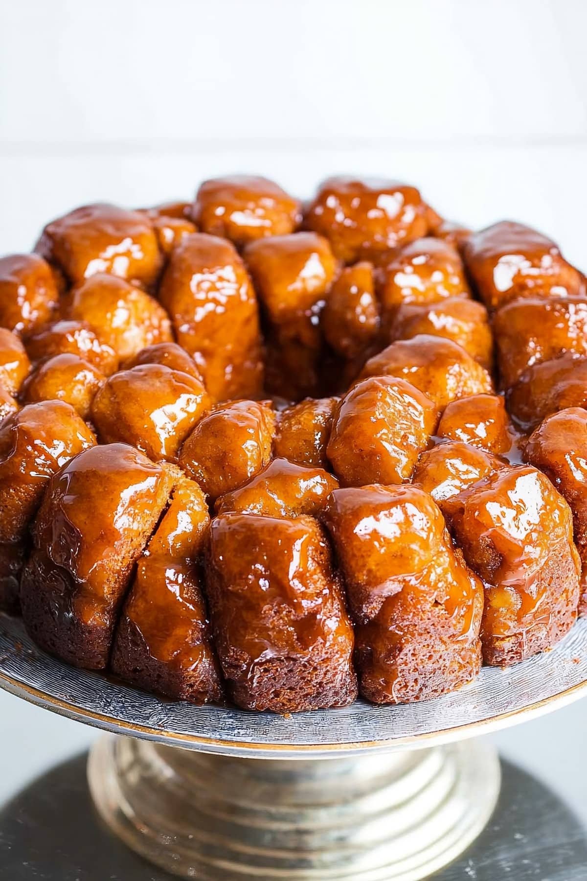 Sticky monkey bread made with biscuits on a cake tray dripping with butter and brown sugar sauce. 