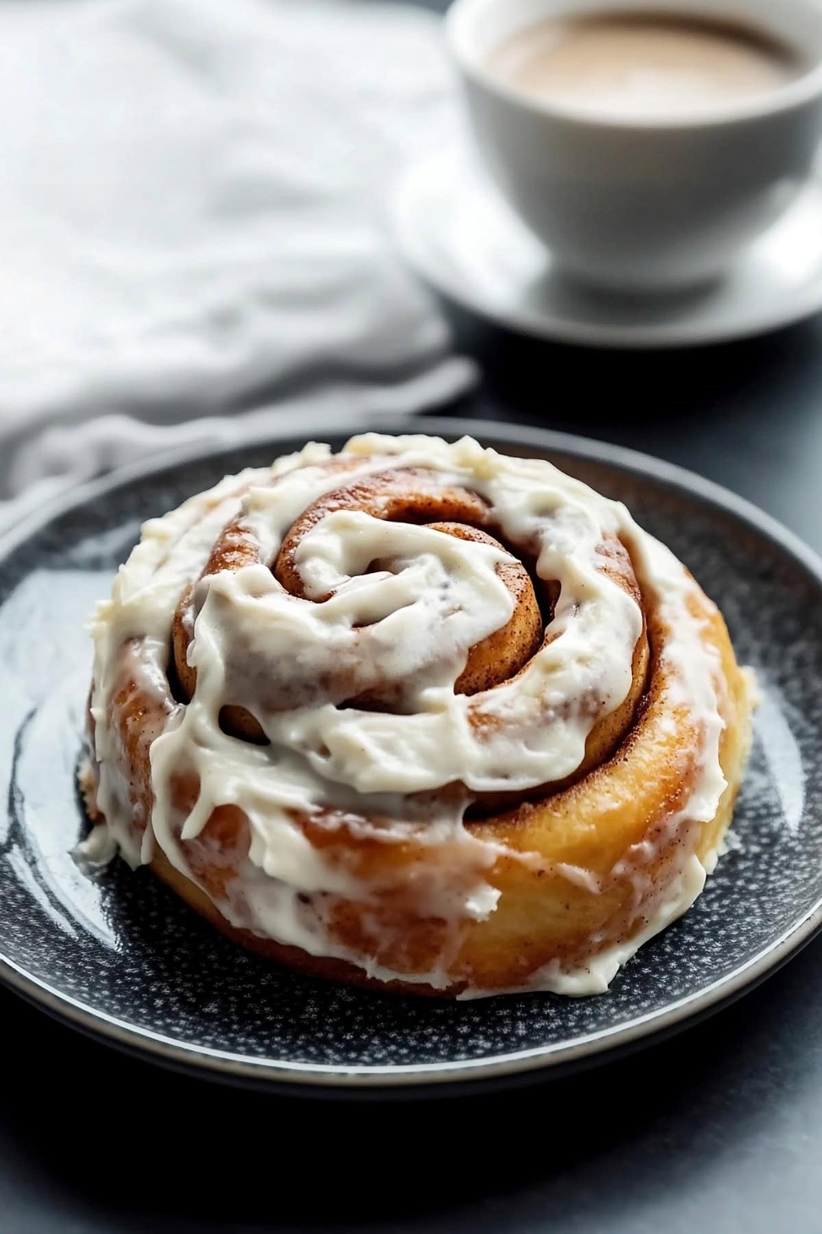 Cinnamon roll with icing served on a plate.