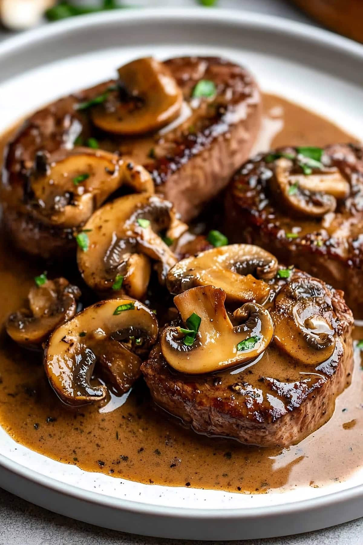 Steak Diane in a bed of sauce with mushrooms and herbs.