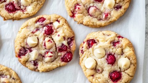 An overhead view of white chocolate raspberry cookies on parchment paper.