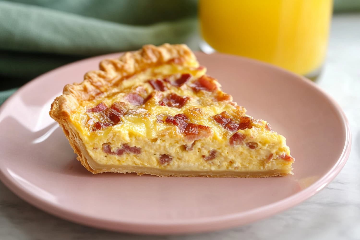 Bacon and cheese quiche cut into a triangular slice, each showing a hearty filling and flaky crust.