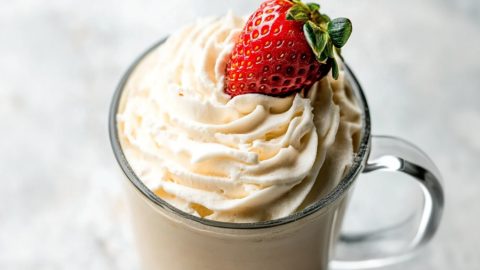 Mug of Baileys whipped cream with fresh strawberry on top.